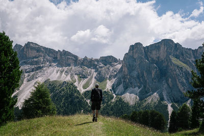 Rear view of hiker walking on mountain against sky