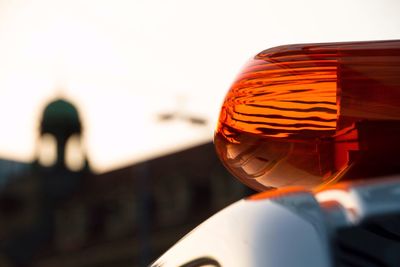 Close-up of red emergency light on car against sky during sunset