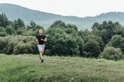 Full length of young man jogging on grassy field