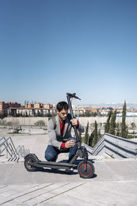 Man with electric scooter on footpath