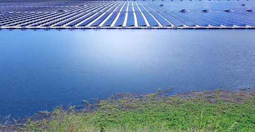 Solar panels float on the surface of the lake with the sky and sunlight reflecting