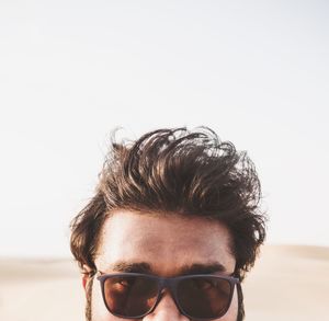 Portrait of young man wearing sunglasses against clear sky