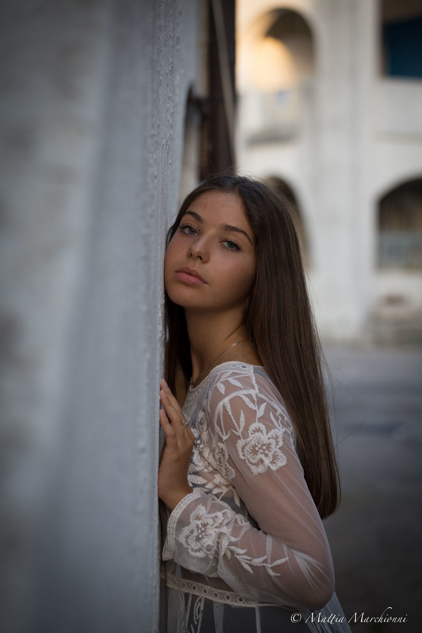one person, young adult, young women, real people, beautiful woman, leisure activity, women, lifestyles, standing, adult, beauty, built structure, architecture, looking, long hair, building exterior, portrait, day, hair, hairstyle, contemplation, architectural column