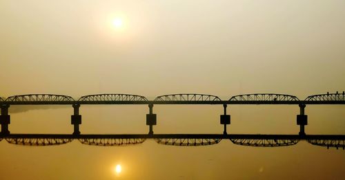 Bridge over river against sky during sunset