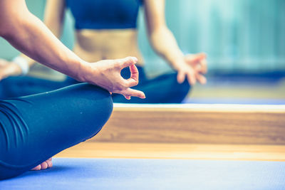 Low section of woman meditating in gym