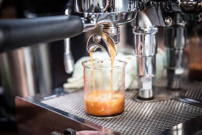 Close-up of machinery pouring coffee in container at cafe