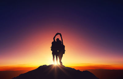 Silhouette man standing on cliff against dramatic sky during sunset