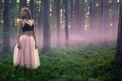 Woman looking away while standing in forest