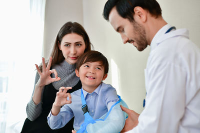 Doctor examining broken hand of boy with his mother in hospital