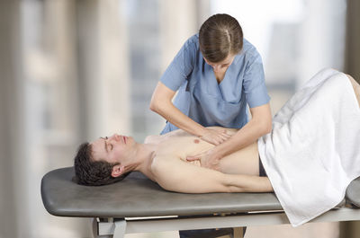 Woman giving massage to man in beauty spa