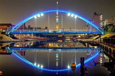 Light trails on bridge in city against sky at night