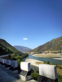 Scenic view of river and mountains against clear blue sky