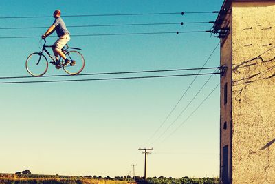 Digital composite image of man riding bicycle on power line