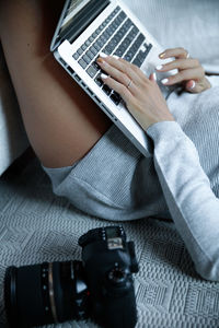 Midsection of sensuous woman using laptop by camera on bed