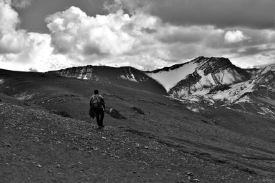 Rear view of men walking on mountain against sky