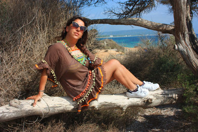 Girl on summer vacation on a log by the sea background of blue water of ibiza balearic island