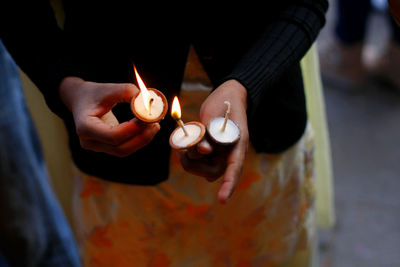 Midsection of woman igniting butter lamp at temple