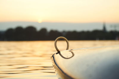 Close-up of padlocks on lake against sky during sunset