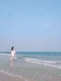 Woman standing on beach against clear sky