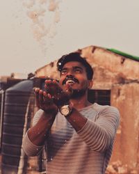 Smiling young man throwing ice during sunset