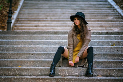 Full length portrait of young woman sitting on staircase