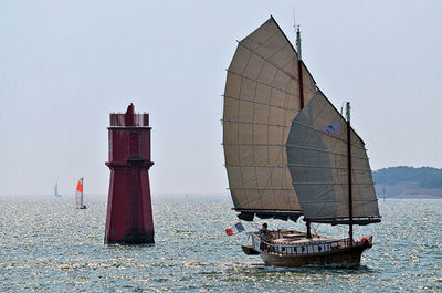 Sailboat in sea against clear sky