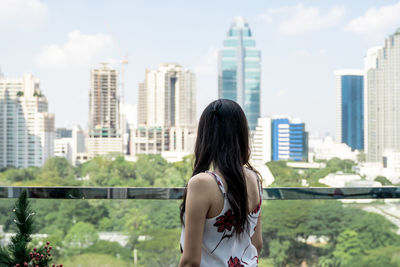 Woman standing against modern buildings in city