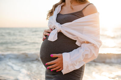 Pregnant woman wear casual dress and shirt over sea nature background outdoor. motherhood. maternity