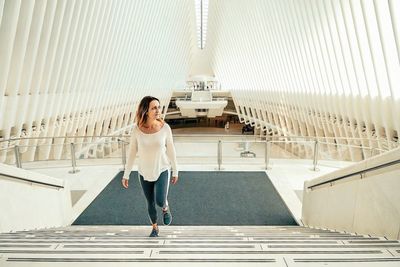 Full length of young woman standing against building