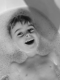 Portrait of smiling boy lying in bathtub