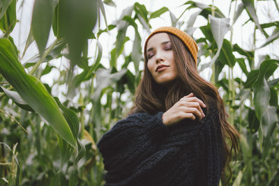 Young woman with eyes closed amidst plants