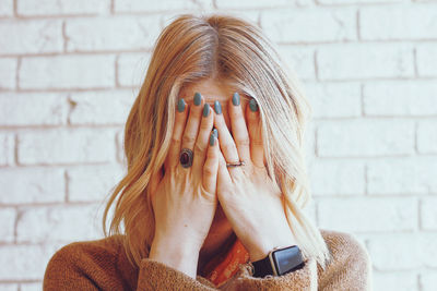 Portrait of woman covering face against wall