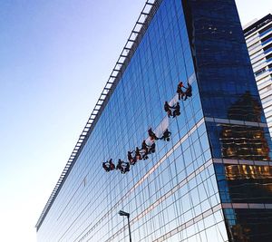 Low angle view of window washers cleaning modern building