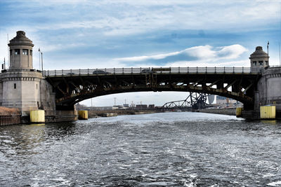 Bridge over river against cloudy sky