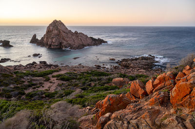 Scenic view of rocks in sea against sky during sunset