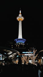 People at illuminated city against clear sky at night