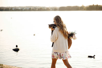 Rear view of woman by lake against sky