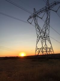 Electricity pylon on field against sky during sunset