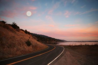 Empty road against sky during sunset