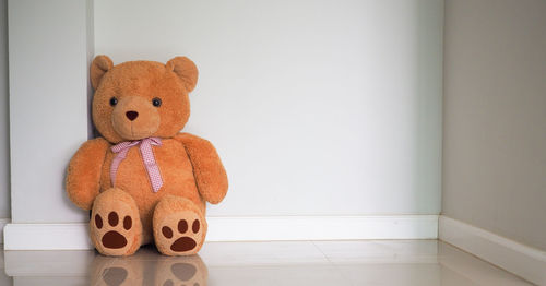 Close-up of teddy bear on floor against wall at home