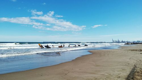 Surfers at beach against sky