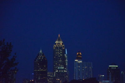 Illuminated buildings against blue sky at night