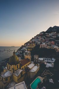 High angle view of townscape by sea against sky during sunset