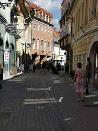 People walking on street amidst buildings in city