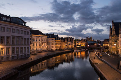 Reflection of illuminated buildings in river against sky