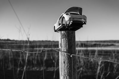 Close-up of wooden post on field against clear sky