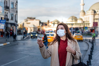 Woman wearing mask looking away standing on street