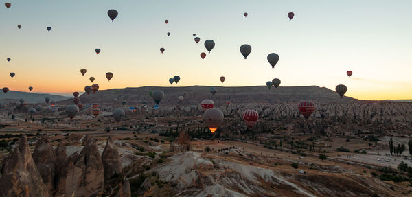 Hot air balloons flying over landscape against sky during sunset