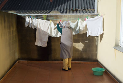 Rear view of woman drying clothes on clothesline