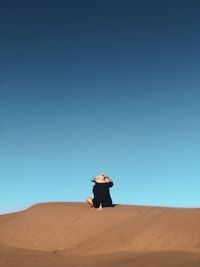 Man in desert against clear blue sky